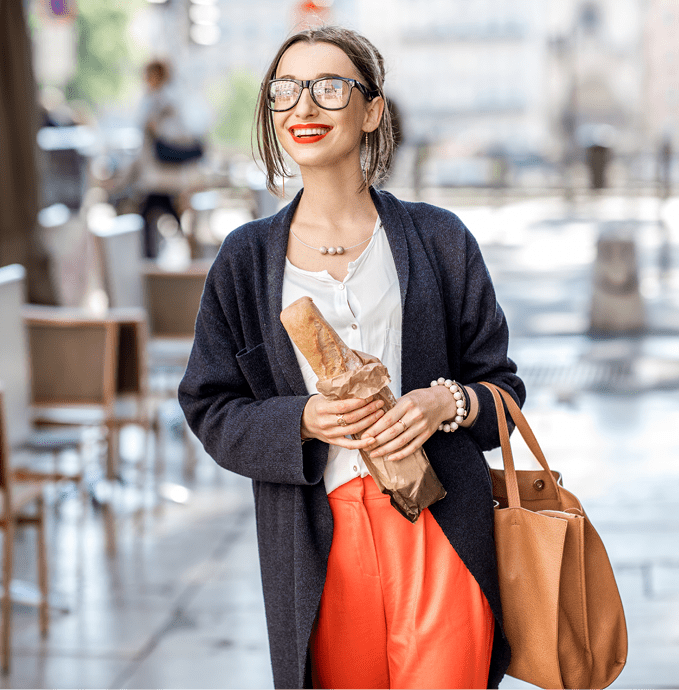 Lifestyle portrait of a french woman walking with bag and baguette on the street with cafes in Lyon city