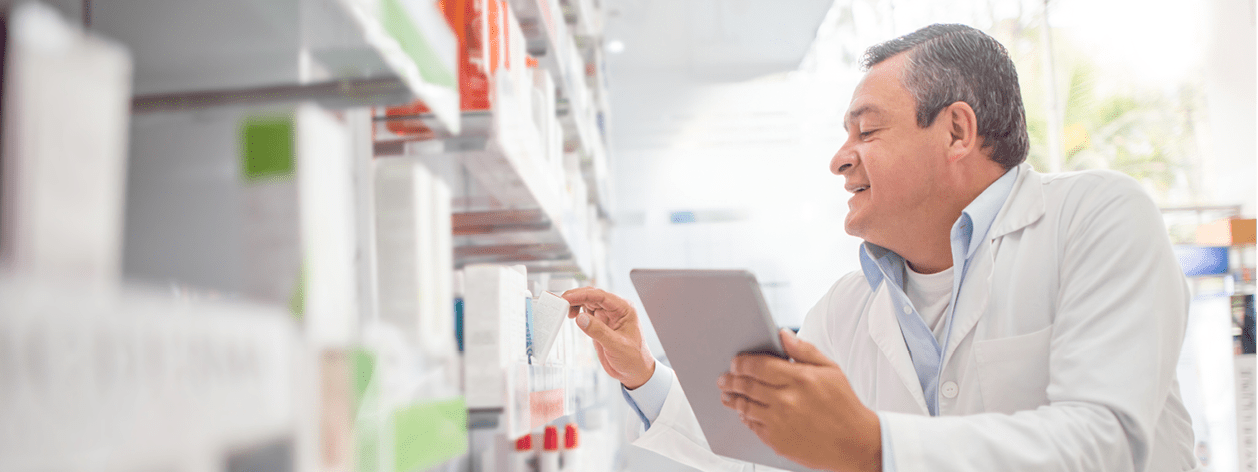 Happy pharmacist doing the inventory at a drugstore using a tablet computer