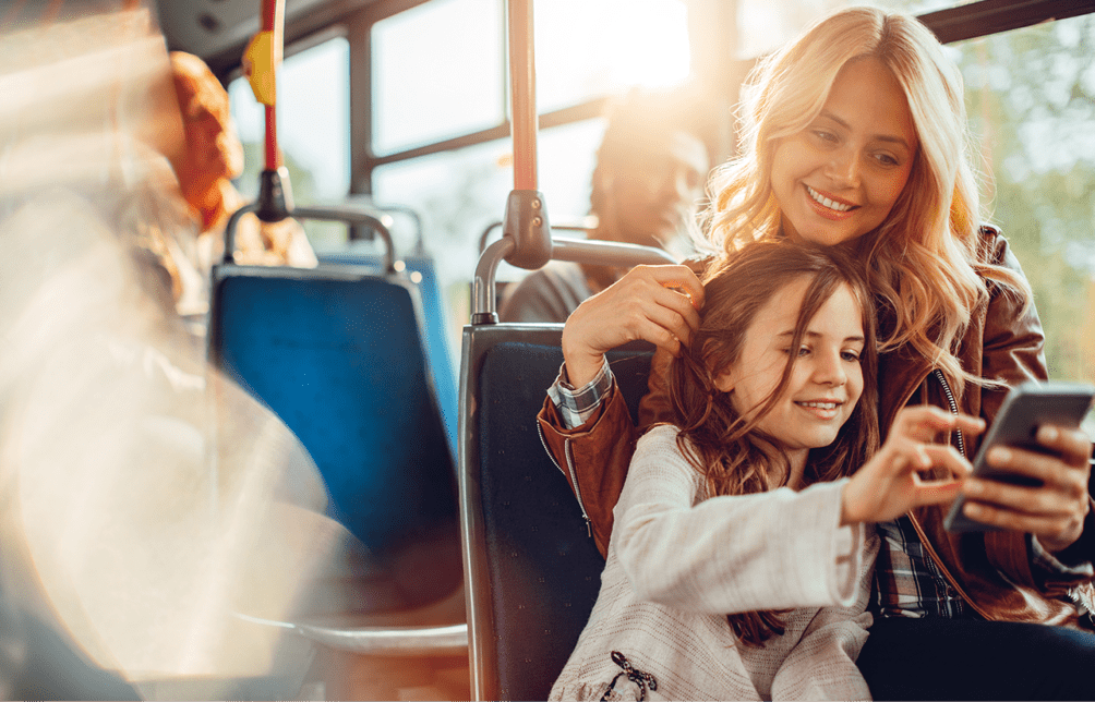 Close up of a mother and daughter using a phone in a bus