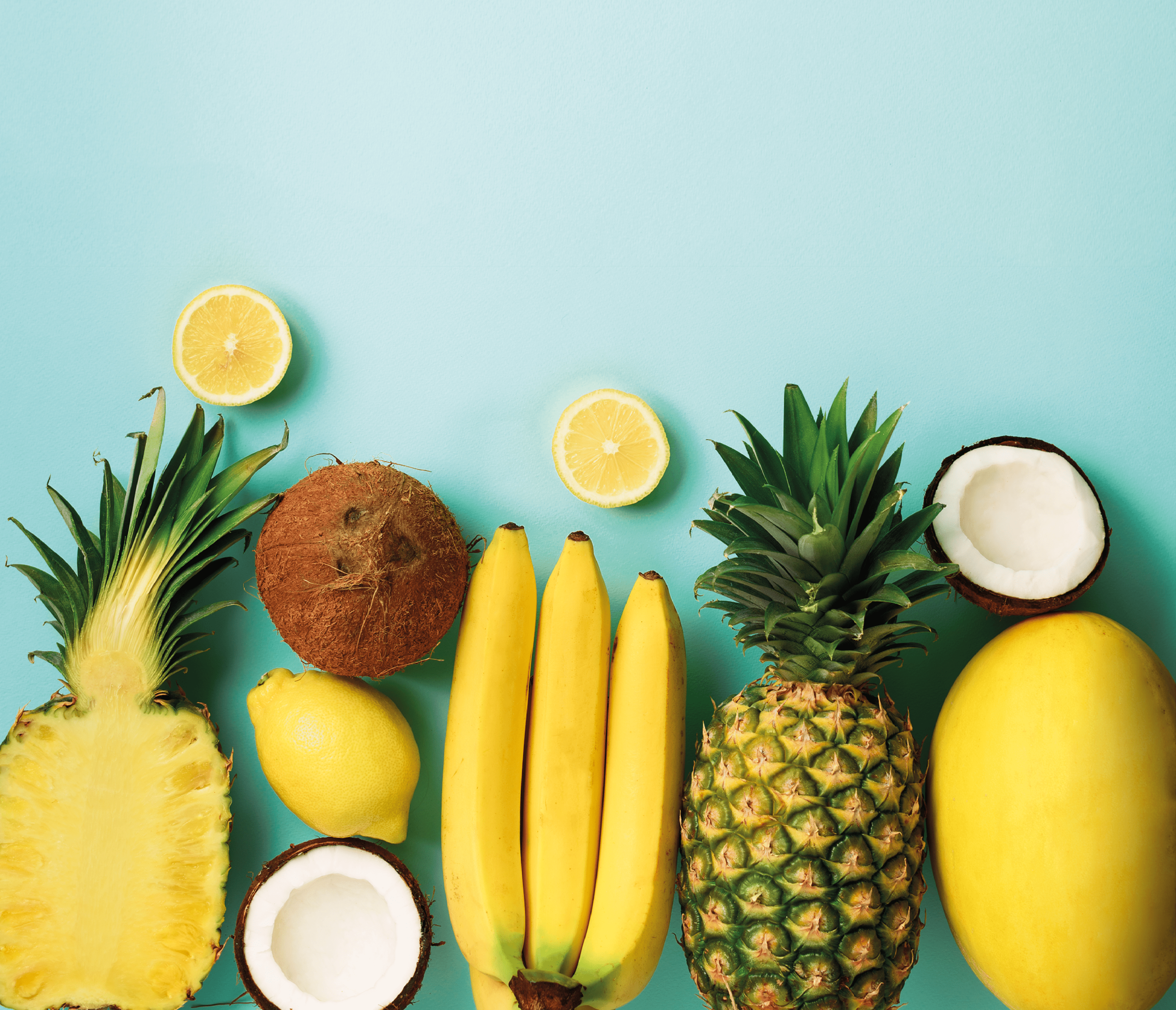 Fresh organic yellow fruits over blue background. Monochrome concept with banana, coconut, pineapple, lemon, melon. Top view. Copy space. Pop art design, creative summer design. Vegan food. Flat lay.