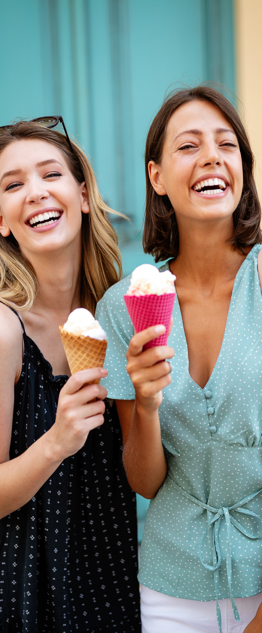 Two young female friends having fun and eating ice cream outdoor