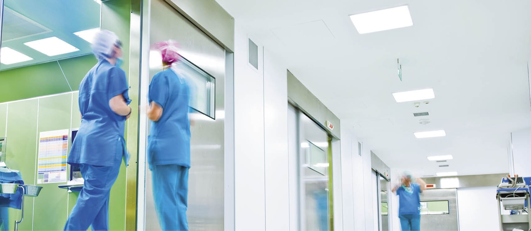 blurred figures wearing medical uniforms in hospital surgery corridor