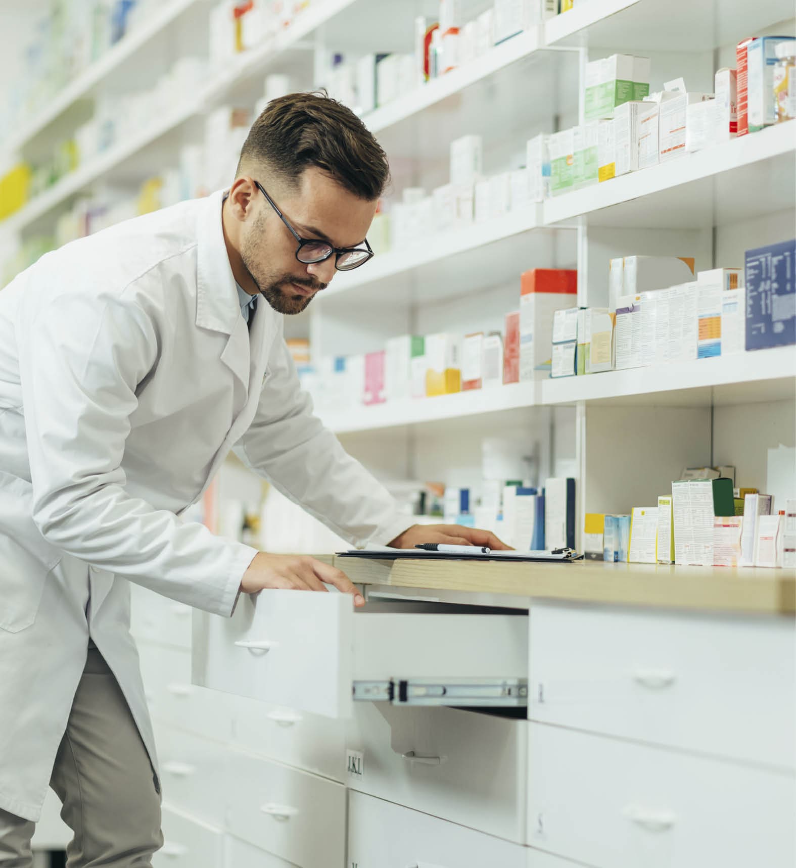 Portrait of a handsome pharmacist working in a pharmacy while checking medications on the shelf