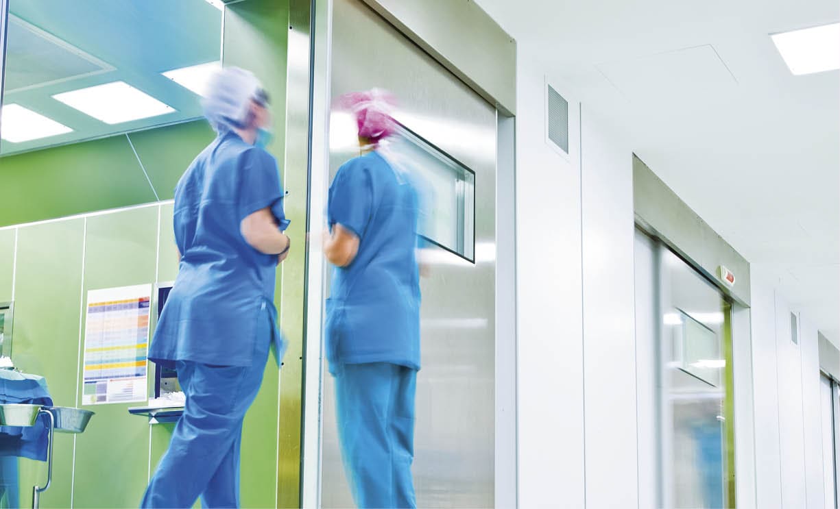 blurred figures wearing medical uniforms in hospital surgery corridor