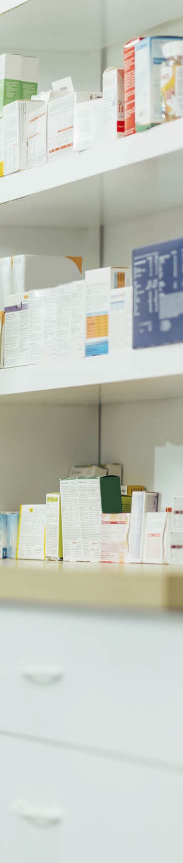 Portrait of a handsome pharmacist working in a pharmacy while checking medications on the shelf