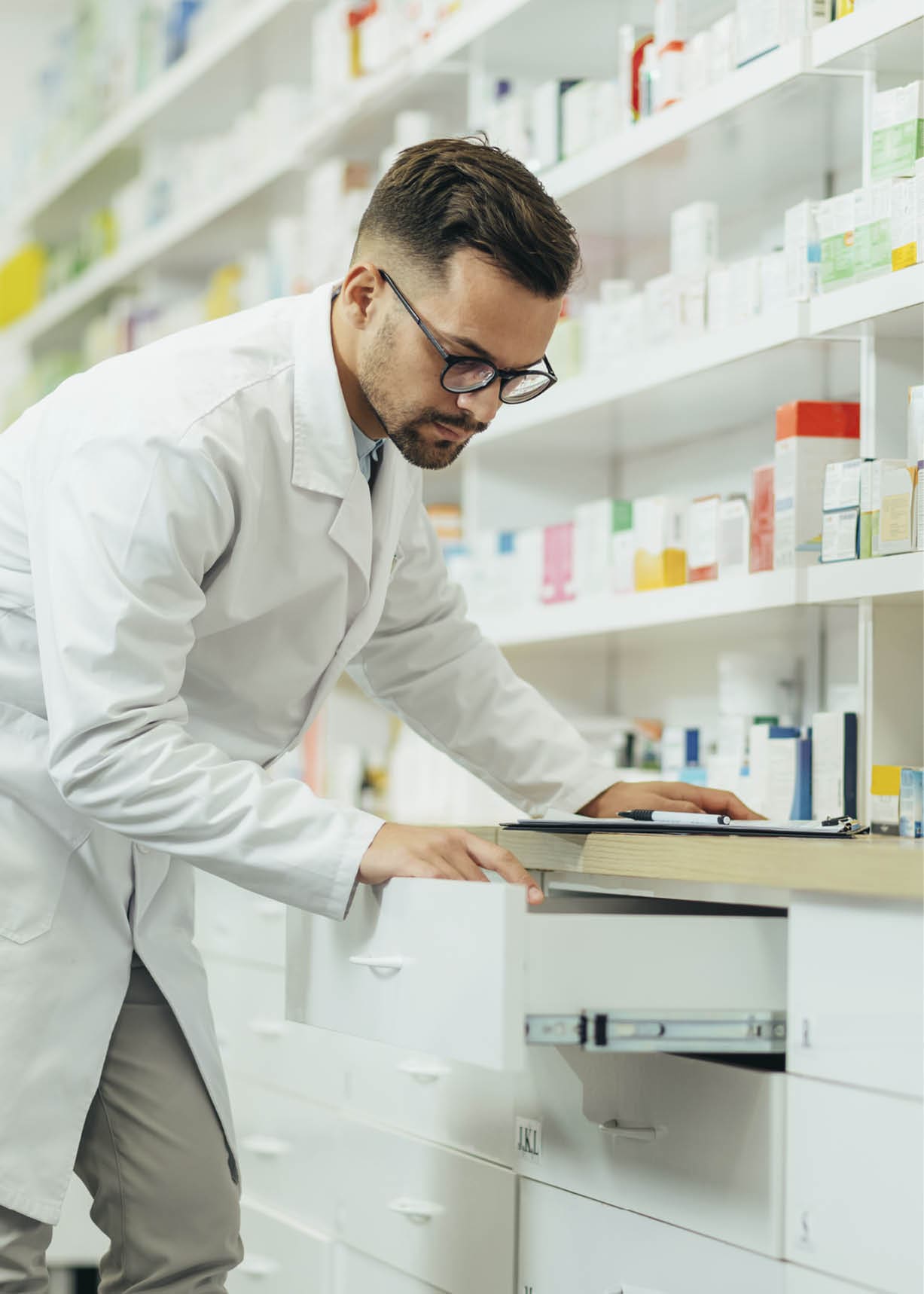 Portrait of a handsome pharmacist working in a pharmacy while checking medications on the shelf